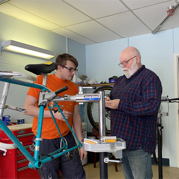bobby teaches a student how to perform bike maintenance
